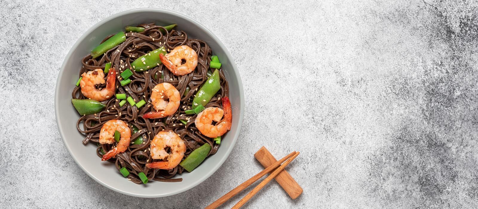 a delicious bowl of savory brown soba noodles topped with shrimp and snap beans